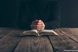 Folded hands and Bible